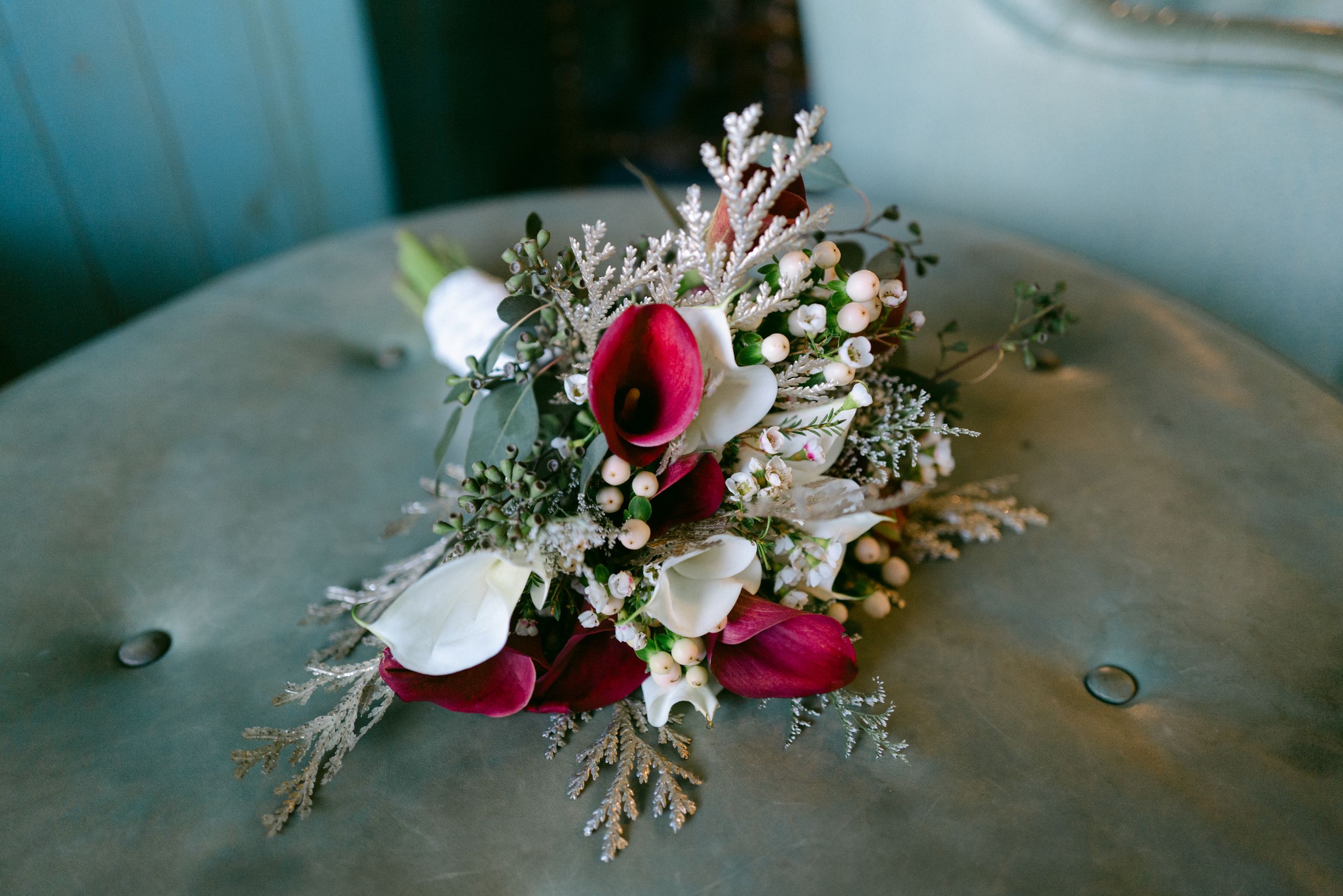 Romantic wedding bouquet featuring deep red and white flowers with delicate greenery.