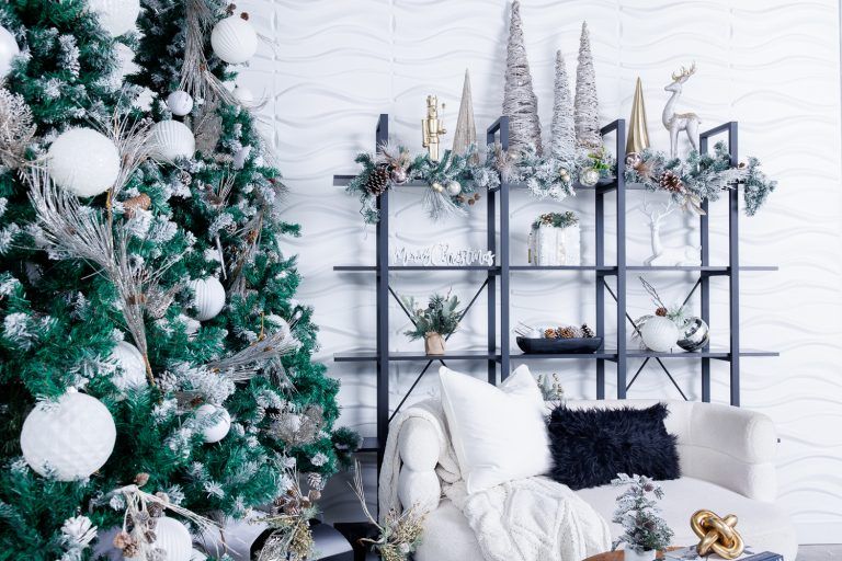 Modern Christmas decor with white tree, industrial shelving, and metallic accents against white brick wall.