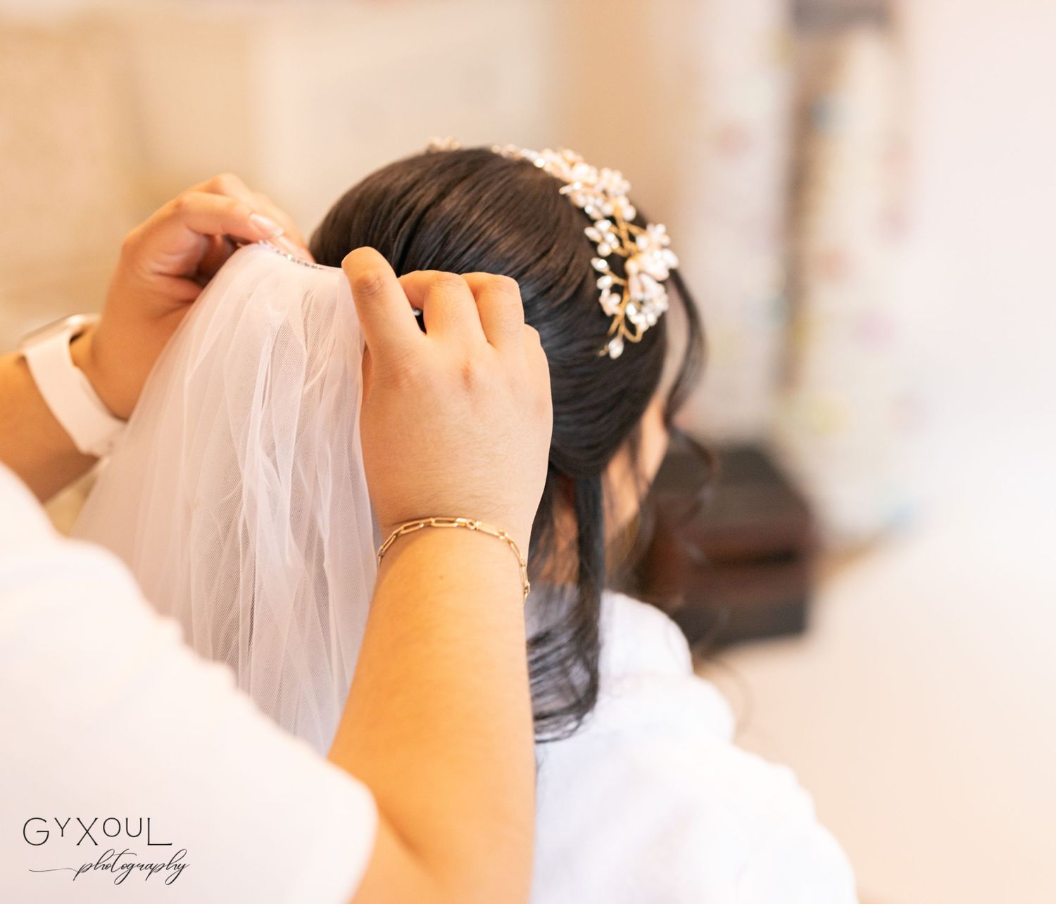Close-up of hands adjusting a delicate bridal veil with pearl hair accessories.