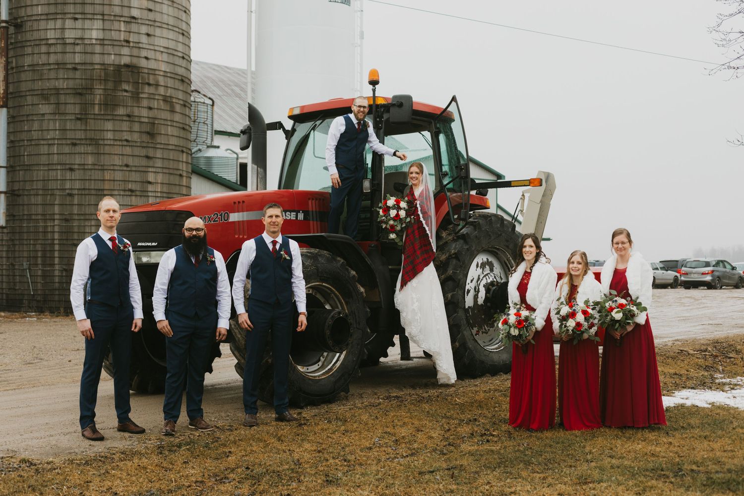 Newlyweds posing together in rustic barn with hay bales.