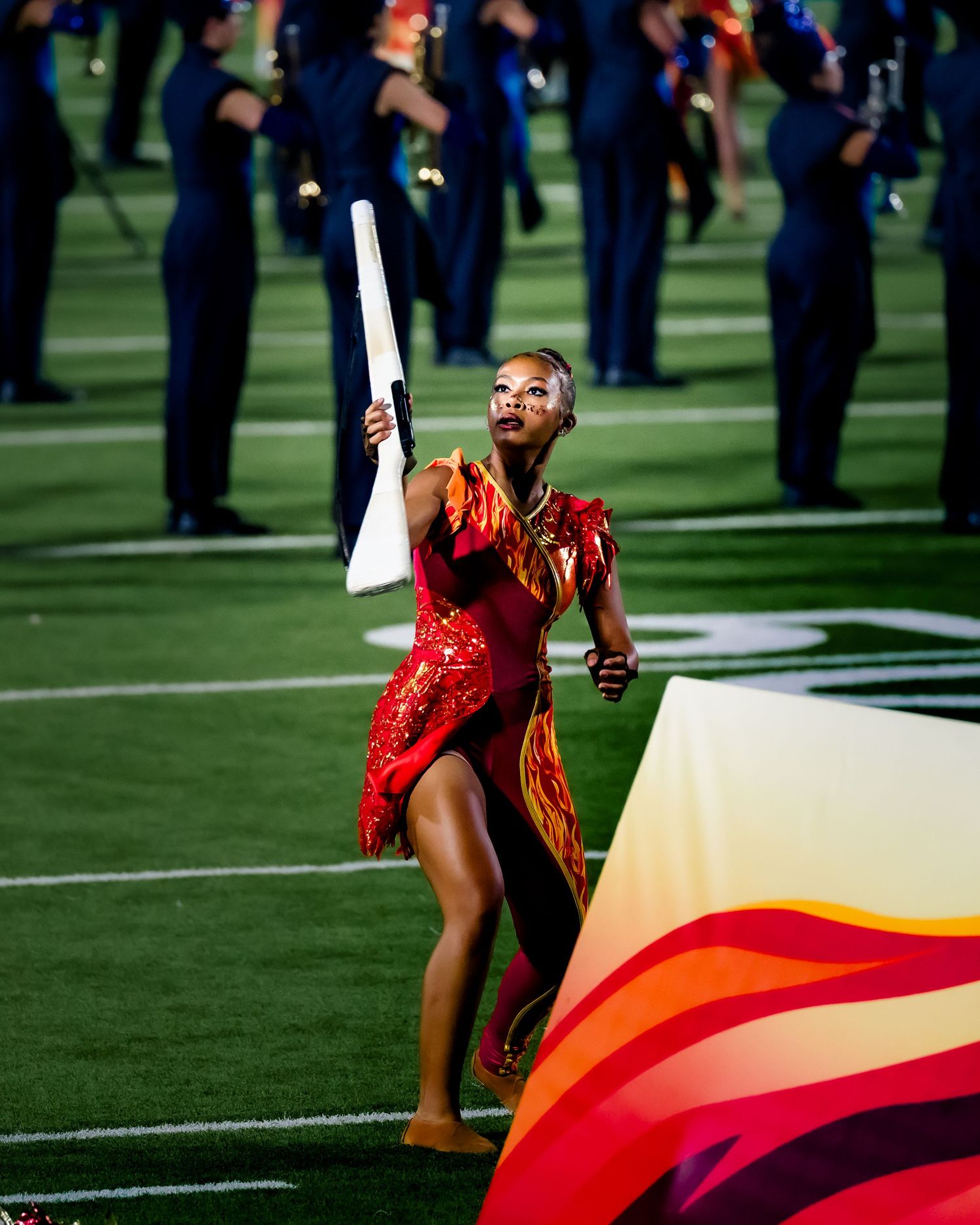 Football player in blue and red uniform reaches to catch ball on field.