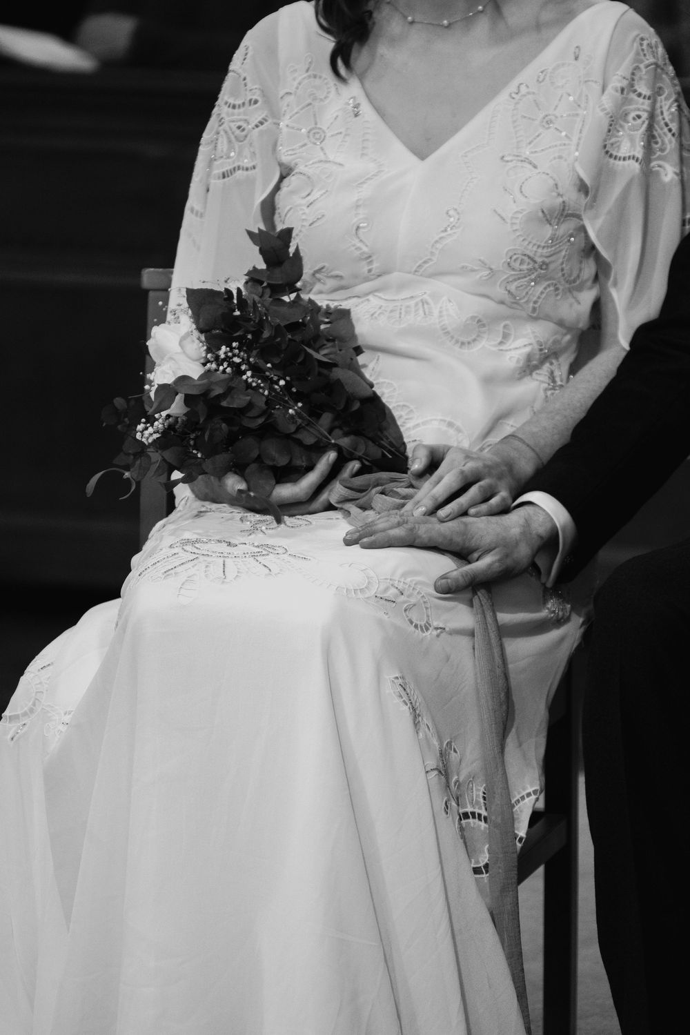 black and white flower bouquet resting on brides knee next to groom, church wedding, cinematic, documentary photos