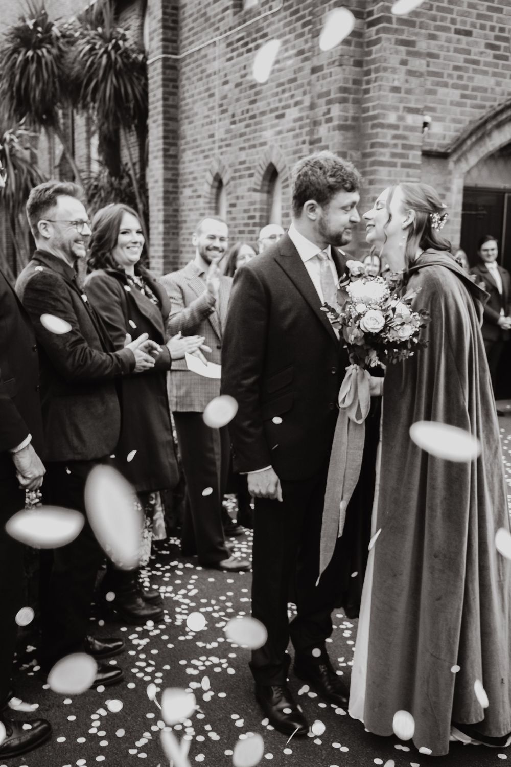 Black and White confetti ceremony shot of the groom in a suit and the bride in a cape. Lord of the rings, fantasy, alternative, Preston