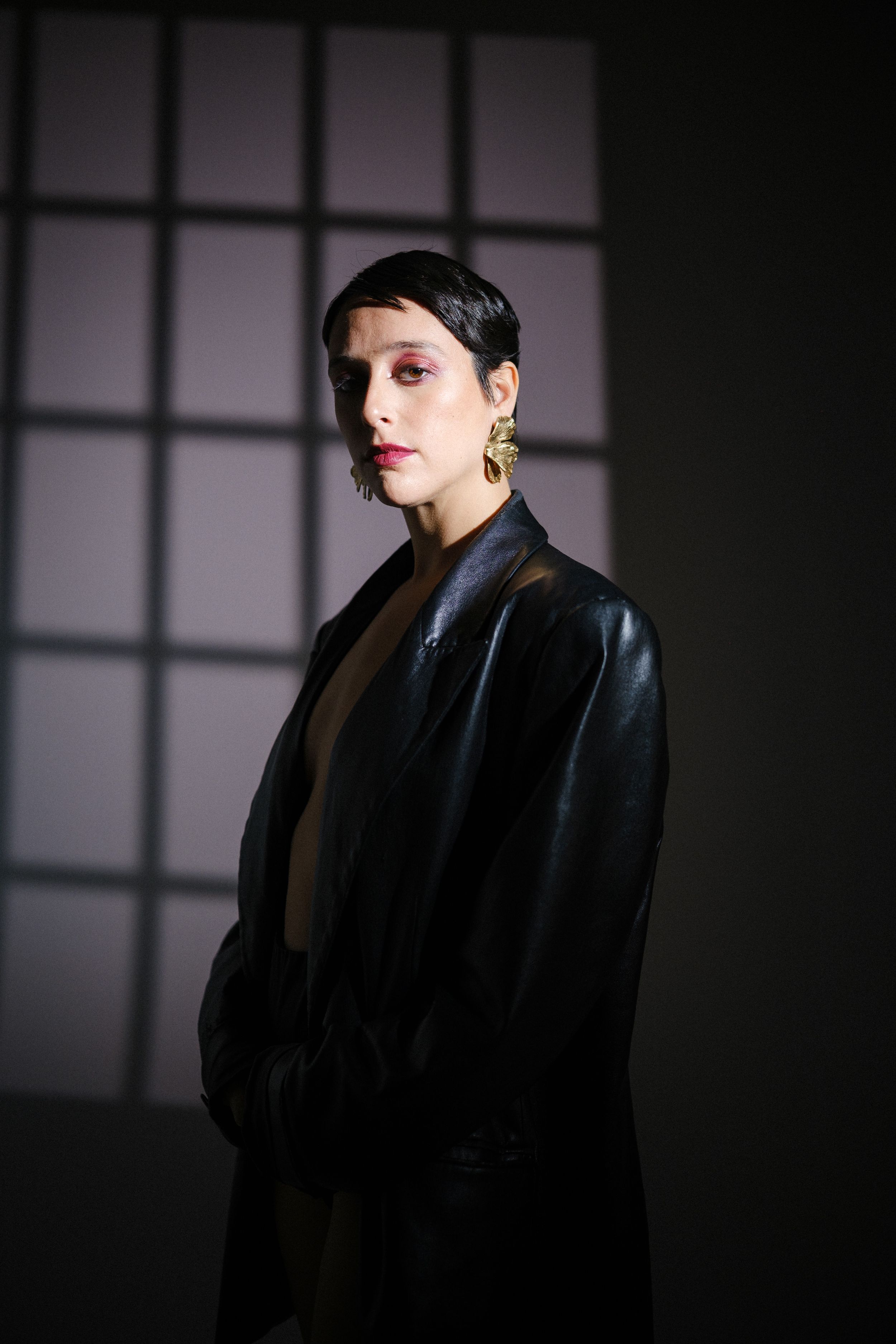 Moody fashion portrait with window shadows and black blazer.