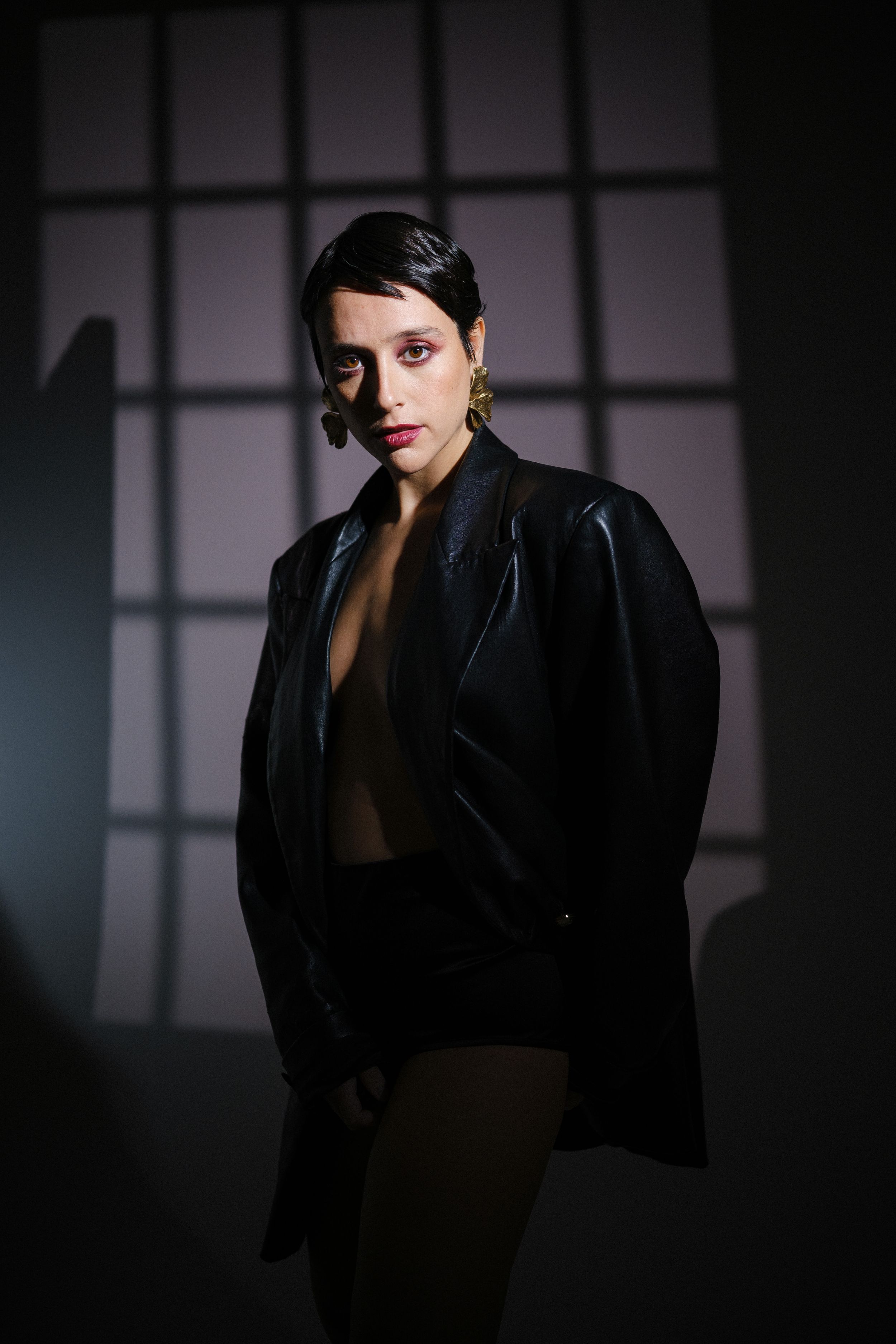 Dark and atmospheric fashion photo with dramatic window lighting.