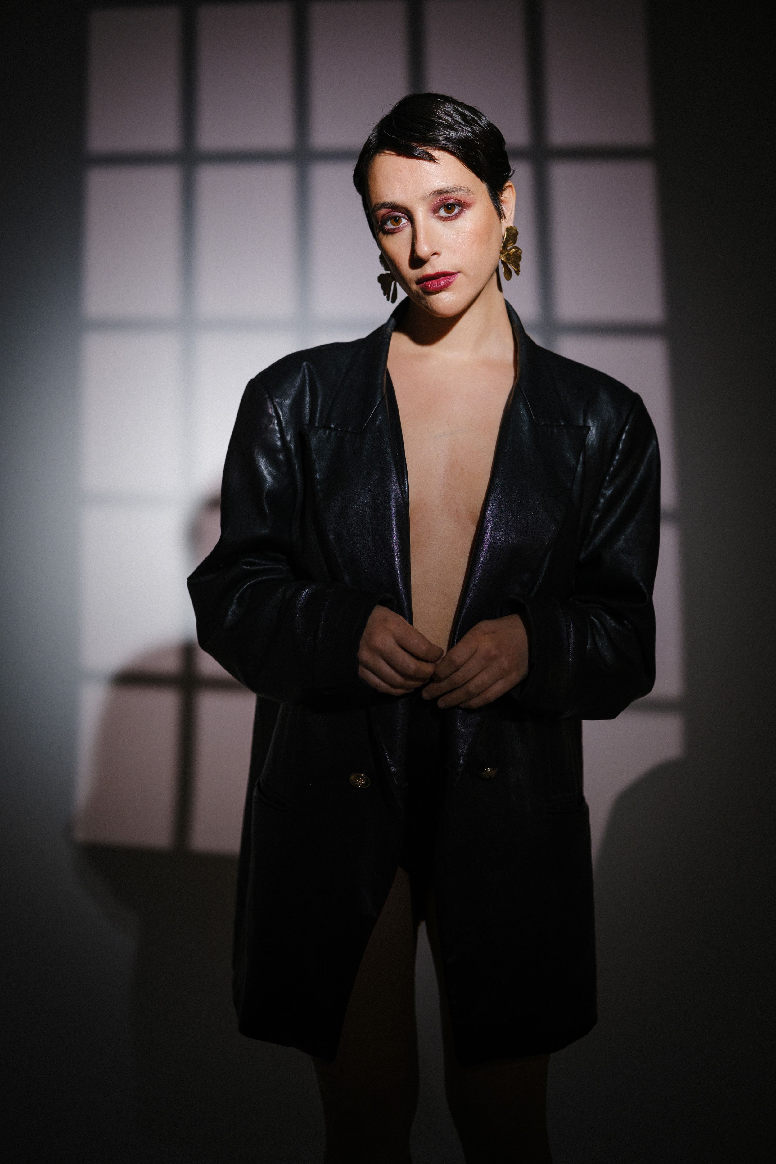 Stylish portrait in black leather blazer with dramatic studio lighting.