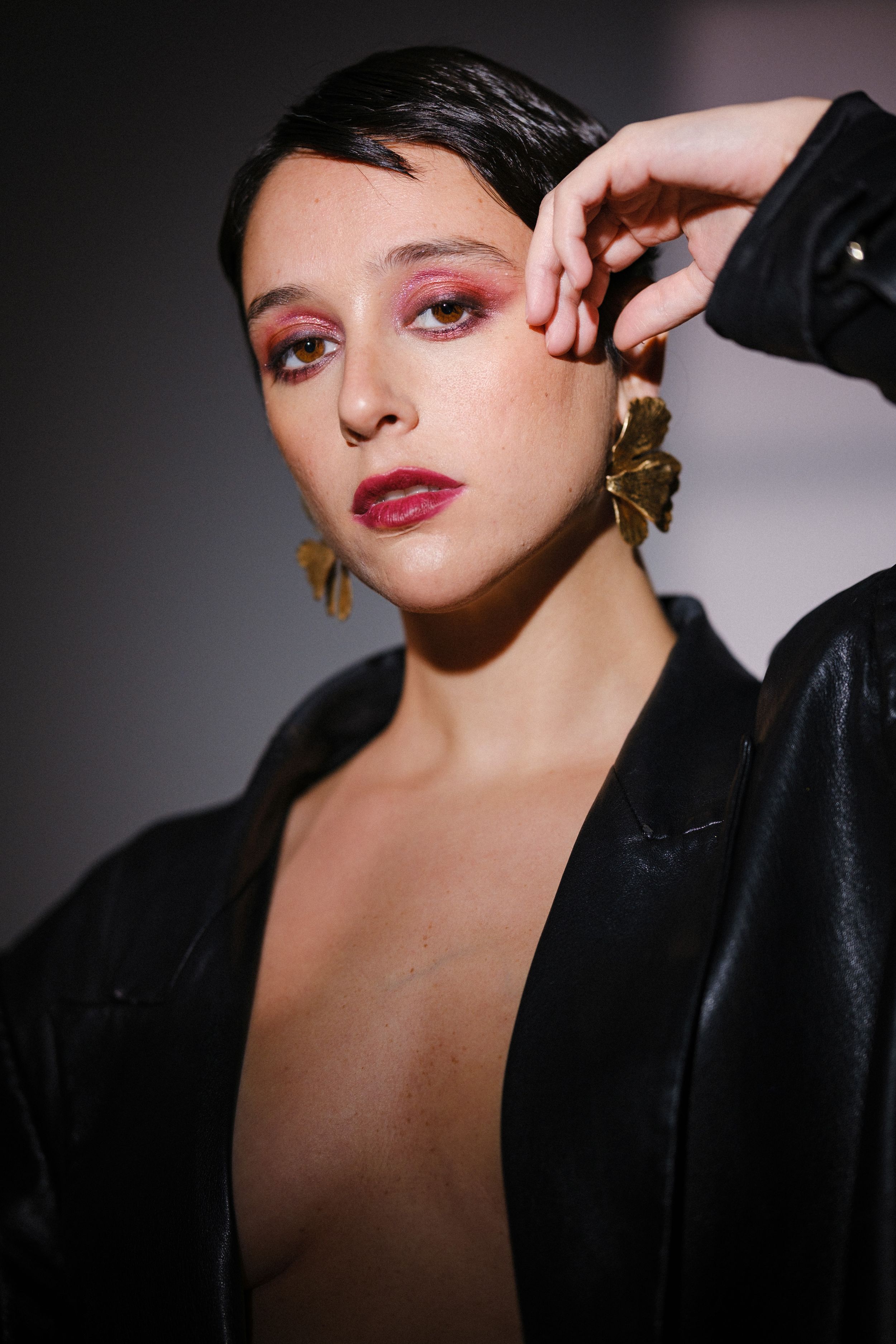 Beauty portrait featuring pink eyeshadow, red lips and gold statement earrings.