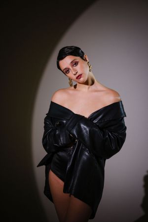 Dramatic studio portrait showcasing black leather off-shoulder design.