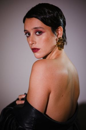 Artistic back view of model in black leather off-shoulder design.