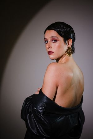 Fashion portrait showcasing dramatic black leather garment in studio lighting.