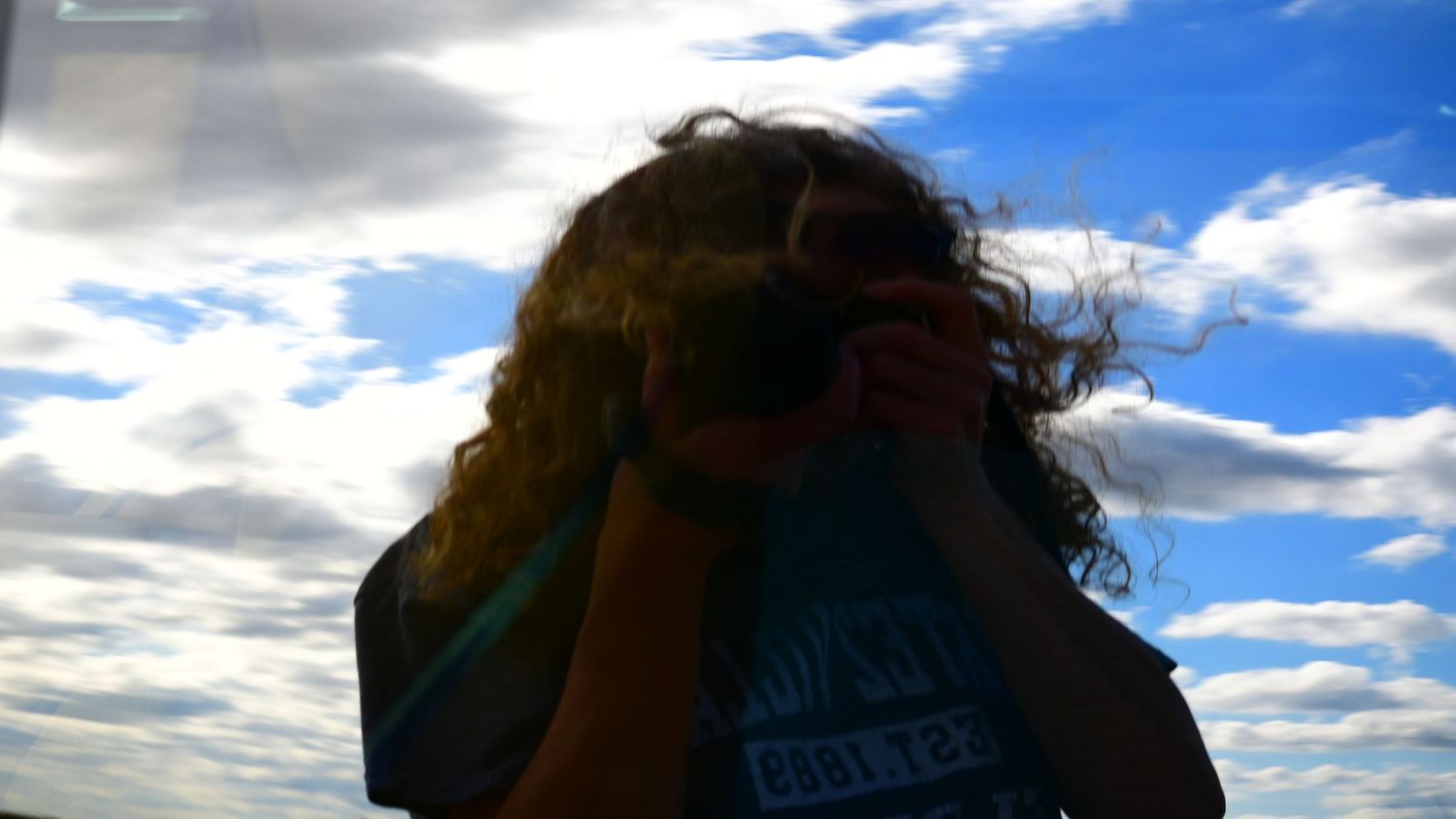 Photographer captures an image in a car window of herself holding the camera.