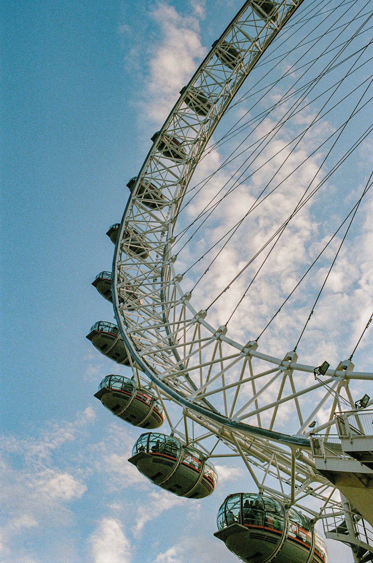 London Eye passenger pods against blue sky captured in vintage film photography style.