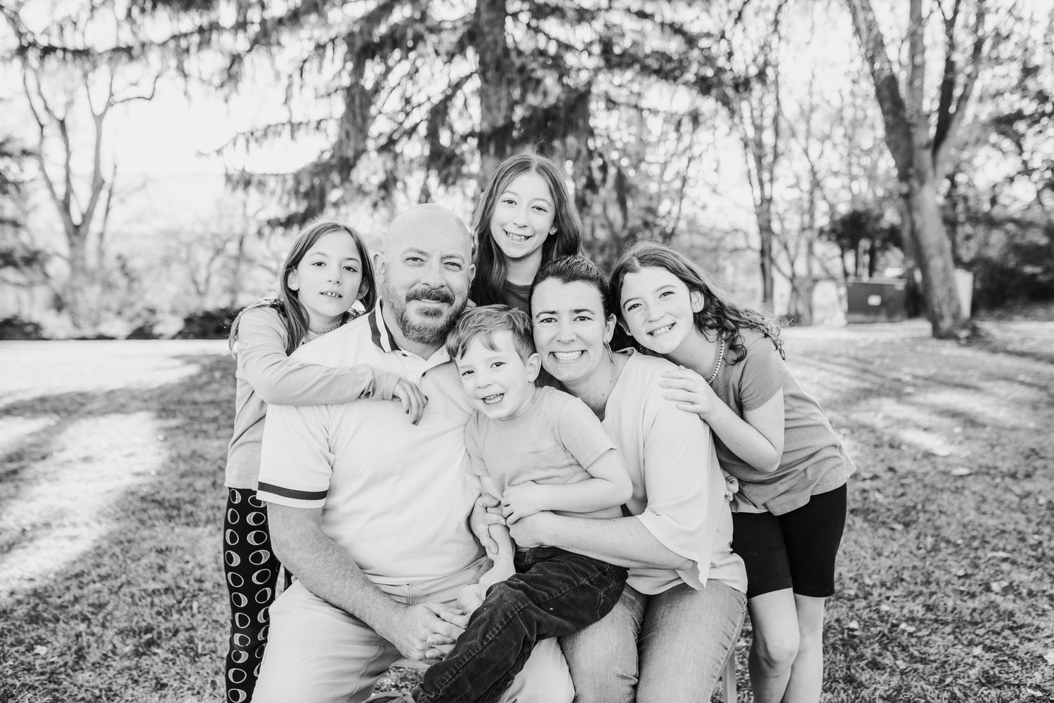 A casual black and white portrait of a playful family group outdoors in a natural setting.
