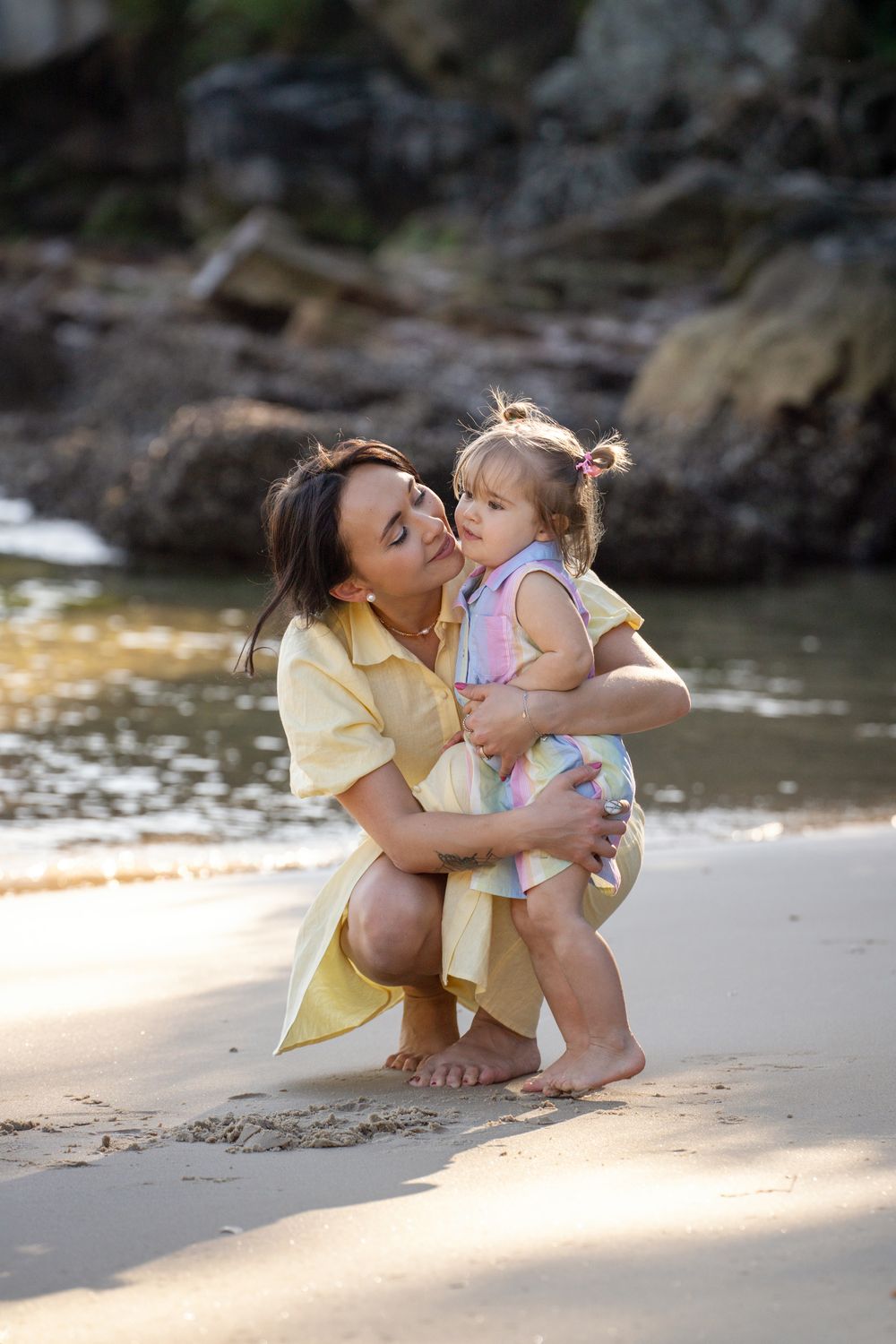Mother giving a sweet kiss to her daughter at Collins Flat Beach during a Northern Beaches family photoshoot