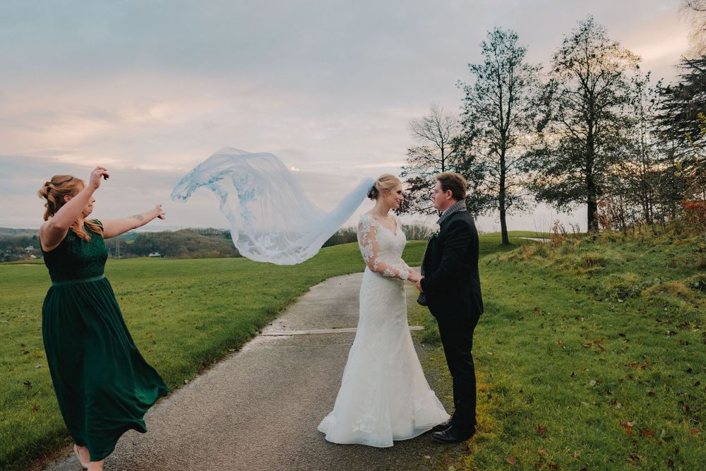 Wedding couple poses together on a winding country path with dramatic autumn skies in the background.