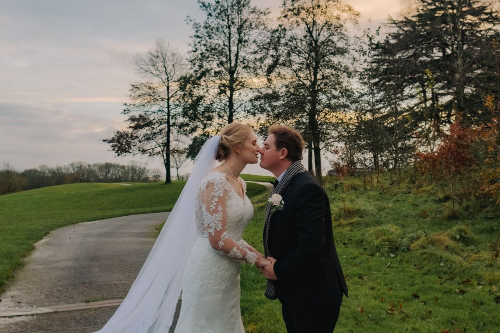 Newlyweds share intimate moments along a rural pathway during golden hour photography session.