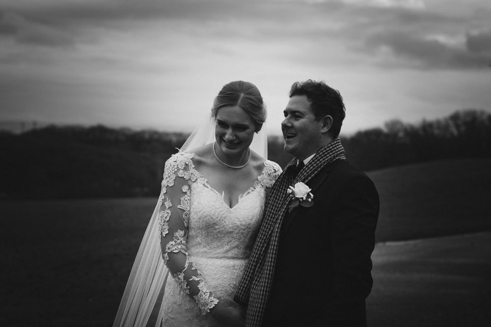 Dramatic black and white wedding portraits captured against moody evening skies.