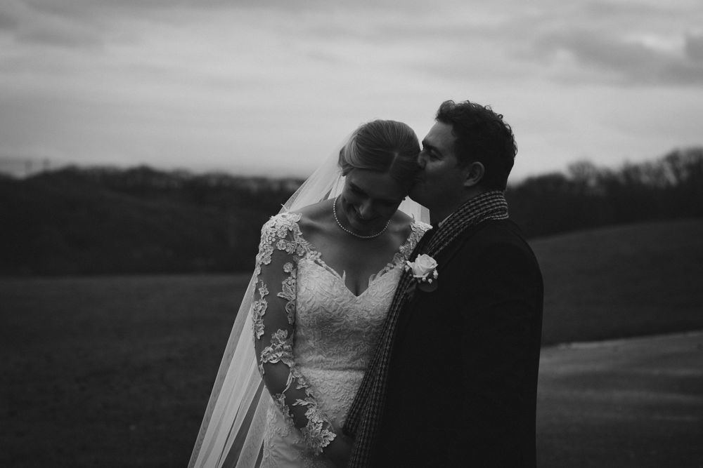 Black and white wedding photos showing tender moments between newlyweds on a rural path.