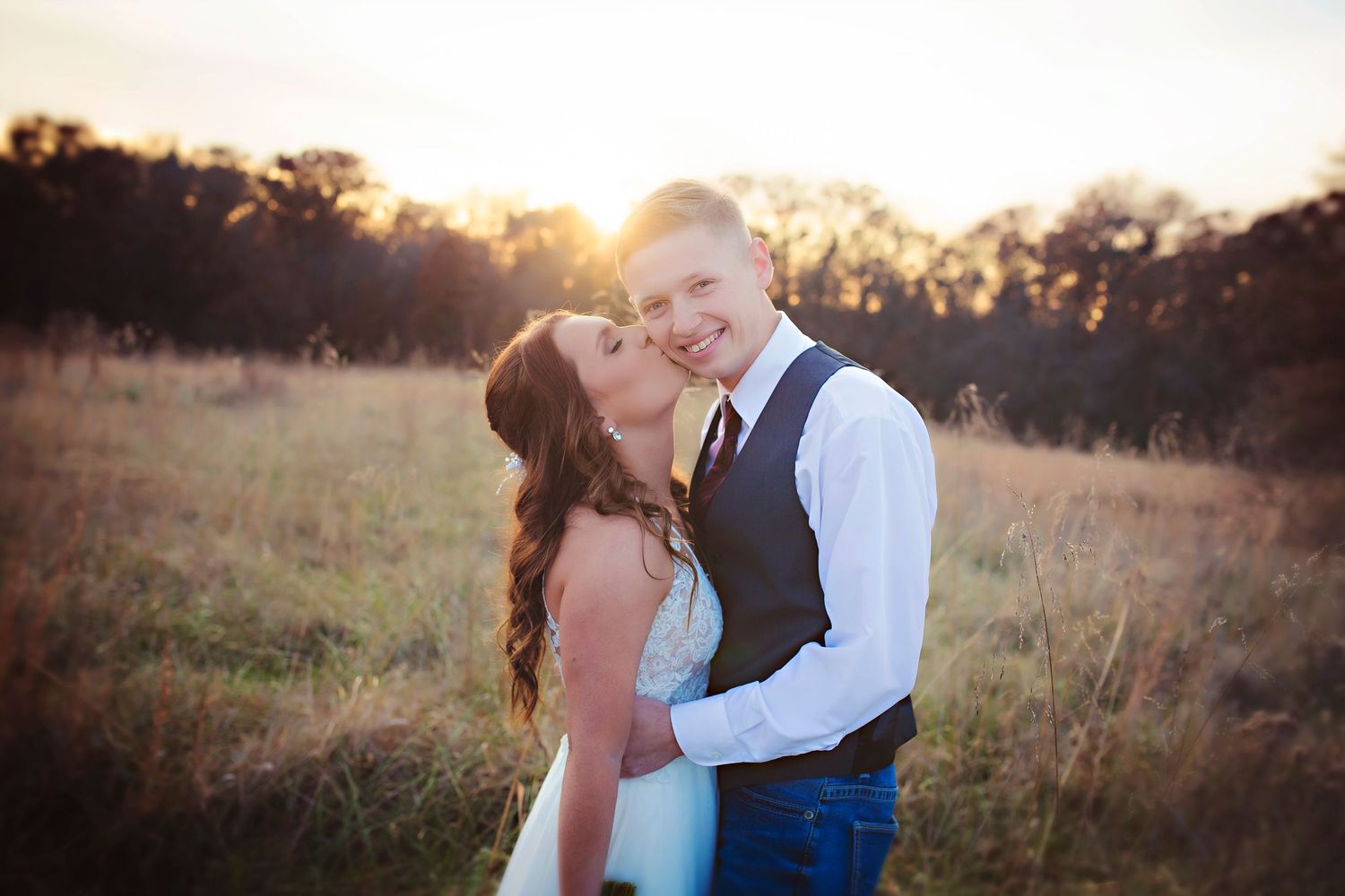 Romantic golden hour engagement photo in rustic field at sunset.