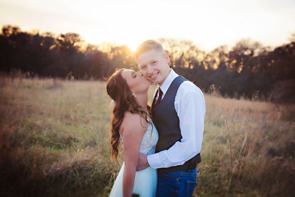 Romantic golden hour engagement photo in rustic field at sunset.