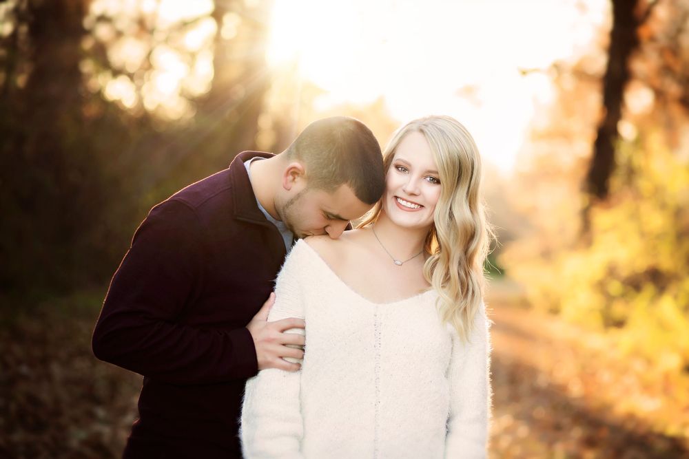 Intimate couple portrait against golden sunset with warm autumn tones.