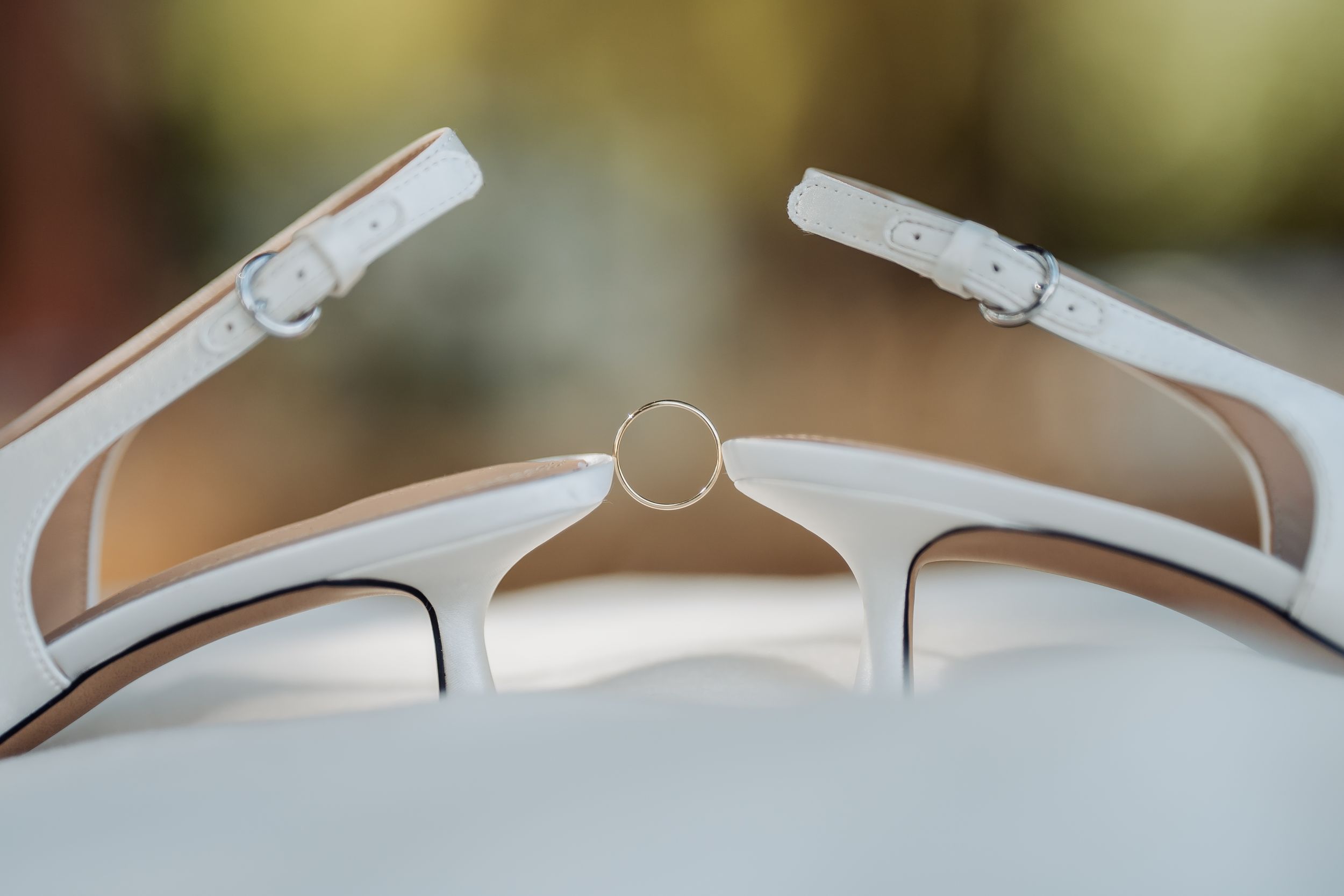 Closeup macro view of white sunglasses frames showing details of hinges and temples against a blurred background.