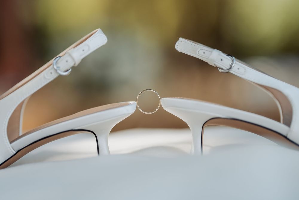 Closeup macro view of white sunglasses frames showing details of hinges and temples against a blurred background.