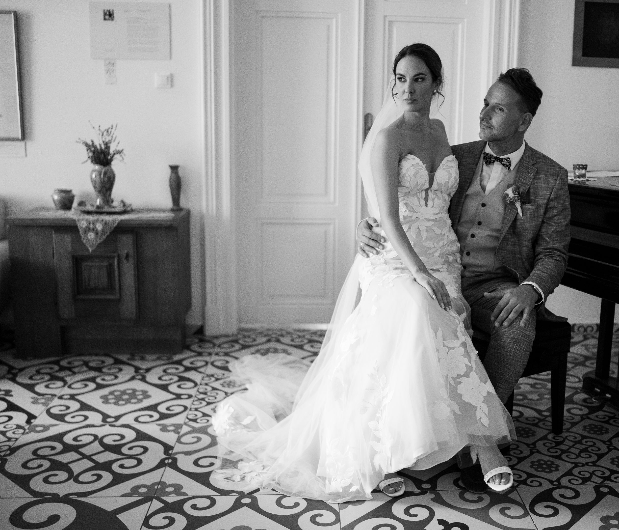 Classic black and white wedding portrait taken in elegant interior room with ornate tiled floor and vintage furnishings.
