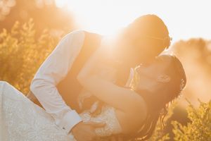 A couple embraces in a golden sunset with lens flare creating a warm romantic atmosphere.