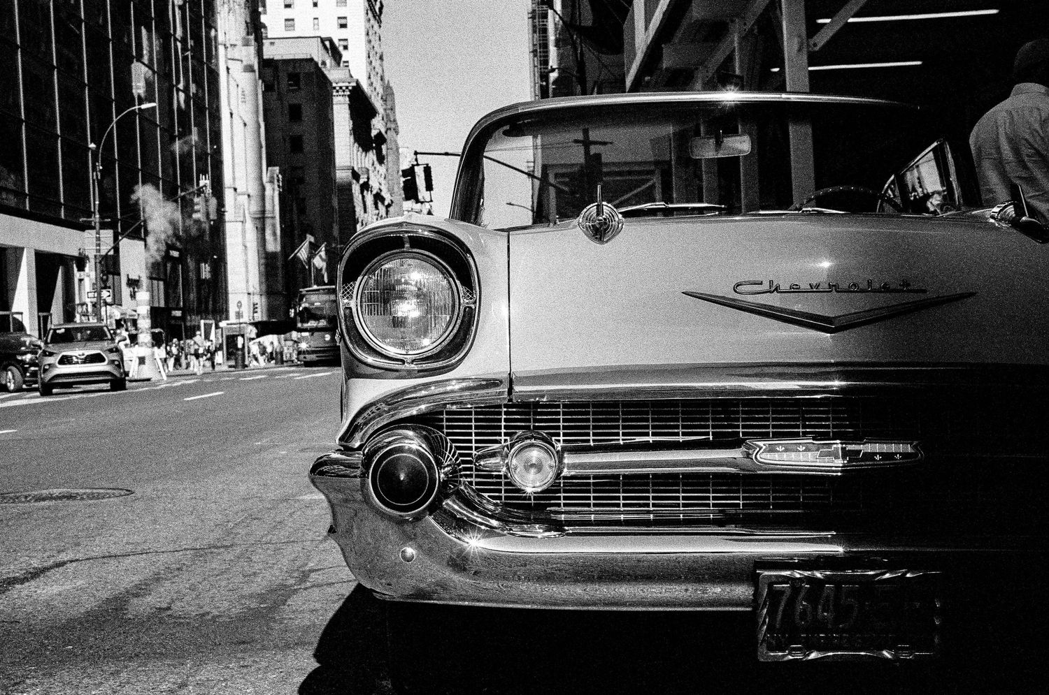 Close up of classic Chevrolet car front grille and headlight on city street.