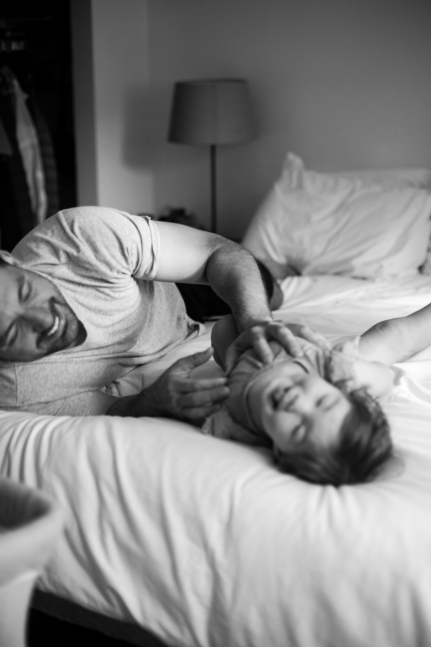 Black and white intimate moment of joyful pair relaxing on bed.