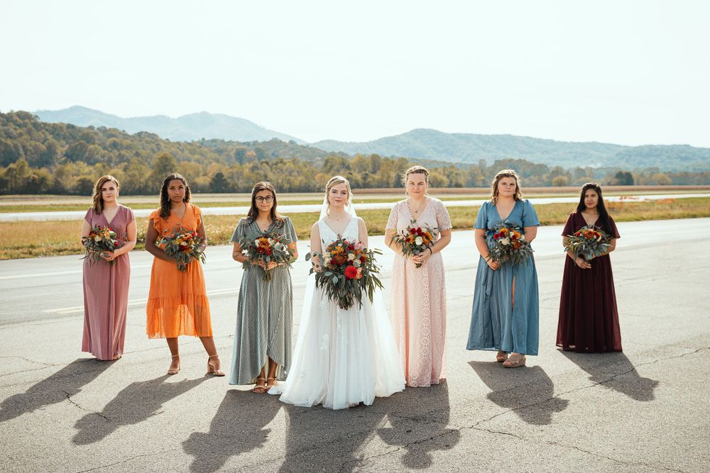Wedding party with bridesmaids in colorful dresses standing against a mountain backdrop.