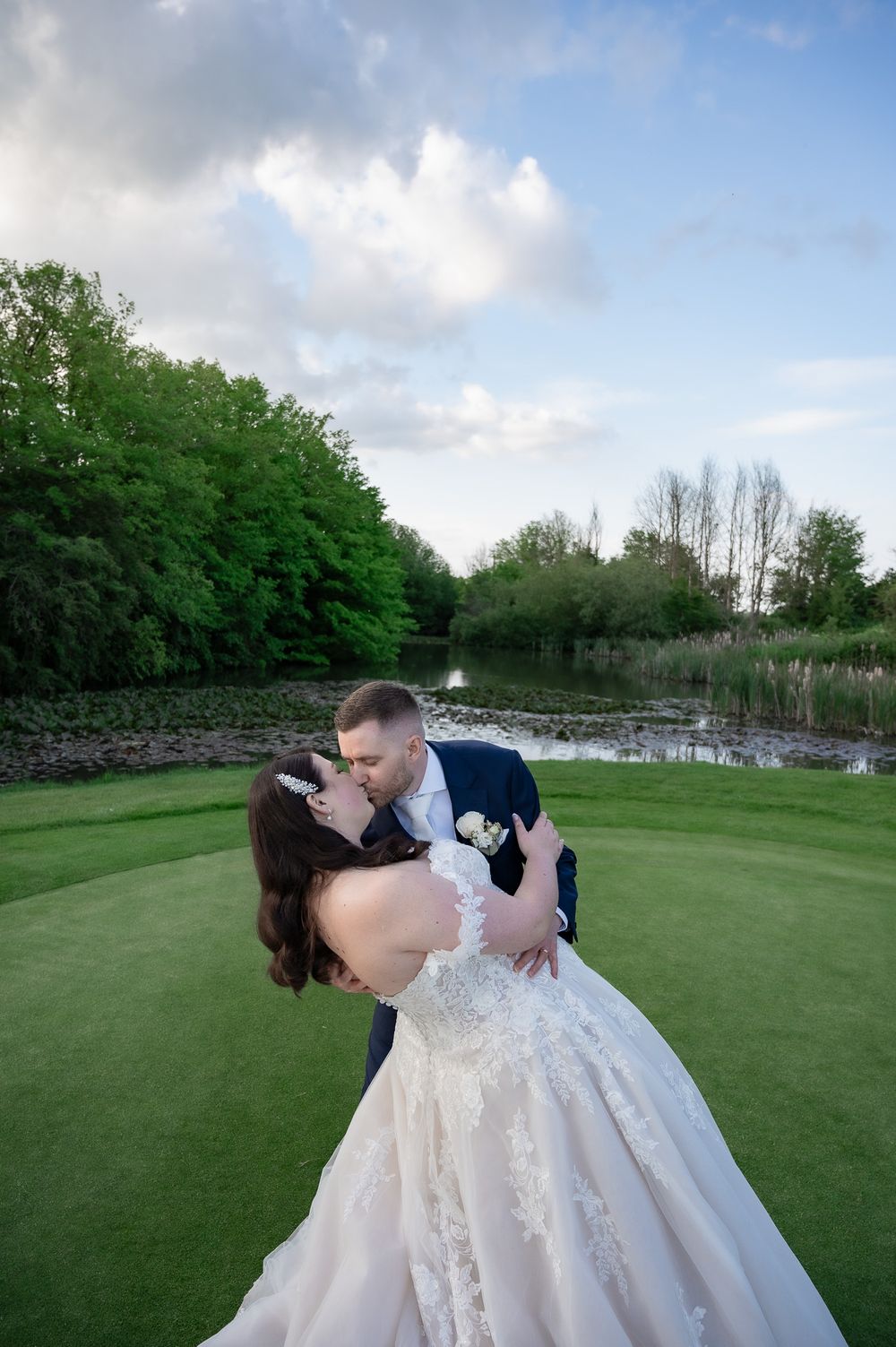 Romantic wedding couple sharing a kiss on a golf course at sunset.