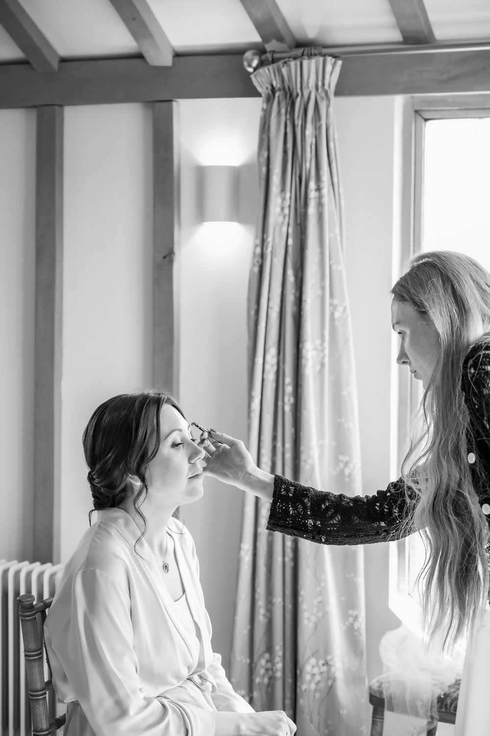 Bride getting professional makeup applied during wedding preparations.
