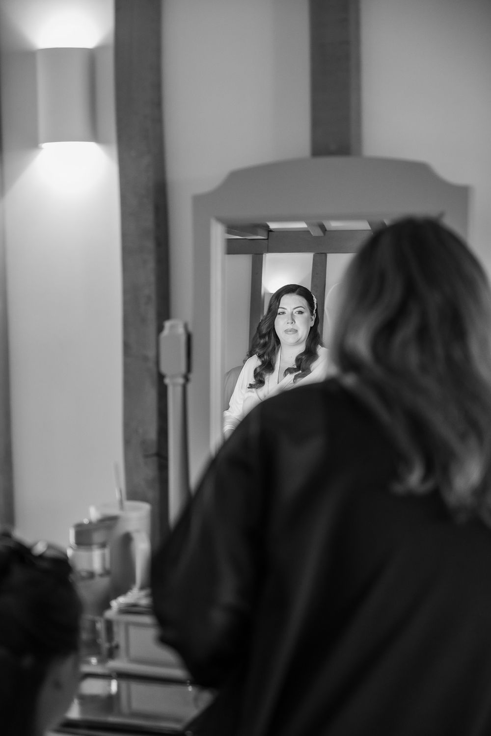 Black and white reflection of bride getting ready in mirror.
