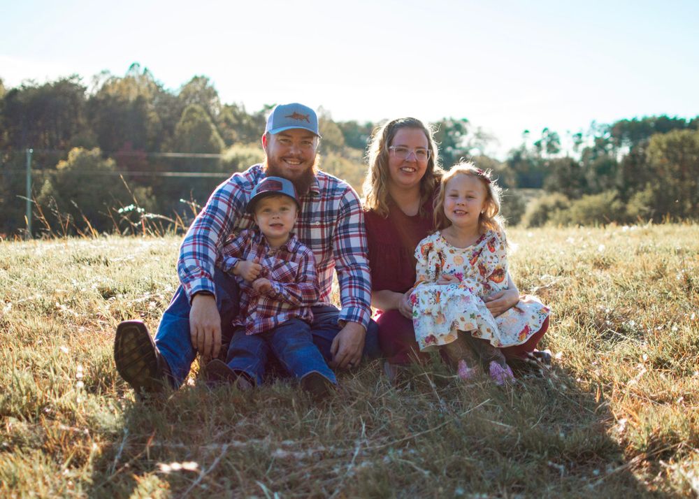 family sitting in a grass field for a family photo session