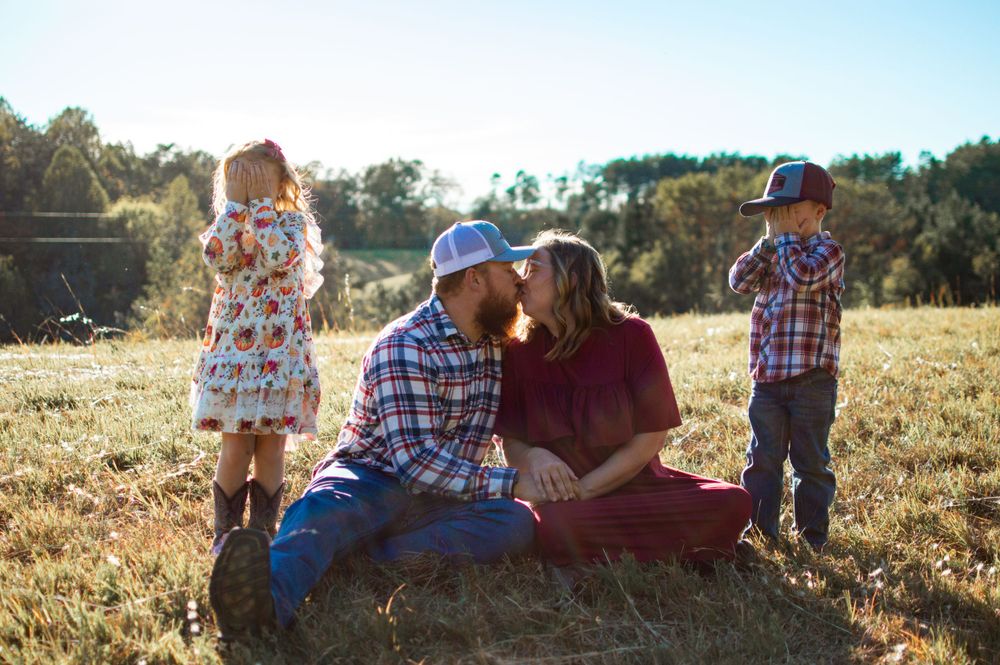 family sitting in a grass field for a family photo session