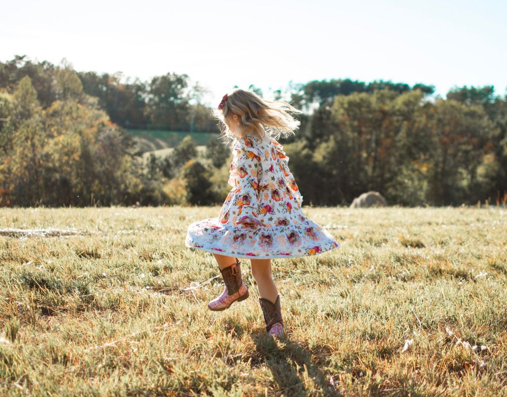child twirling in a grass field for family photo session