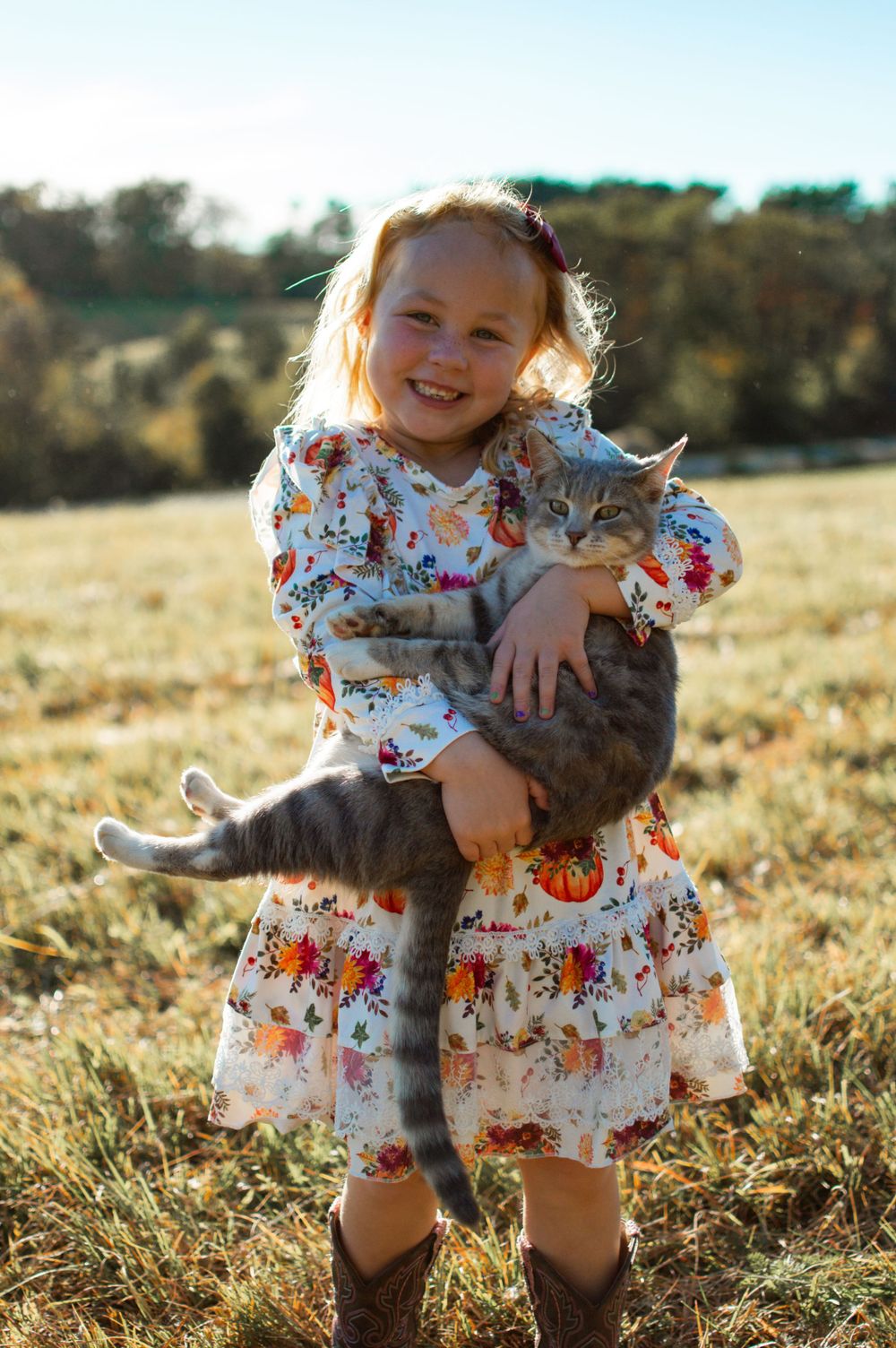child holding a cat in a grass field