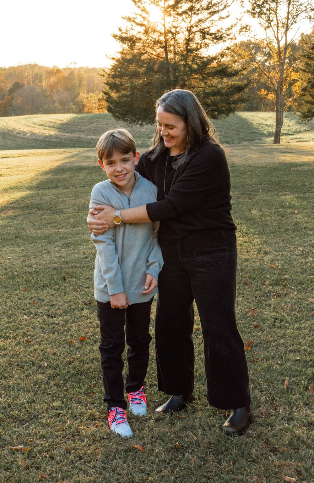 mom and son hugging in a field at sunset posed for a photo session