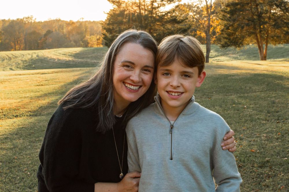 mom and son hugging in a field at sunset posed for a photo session