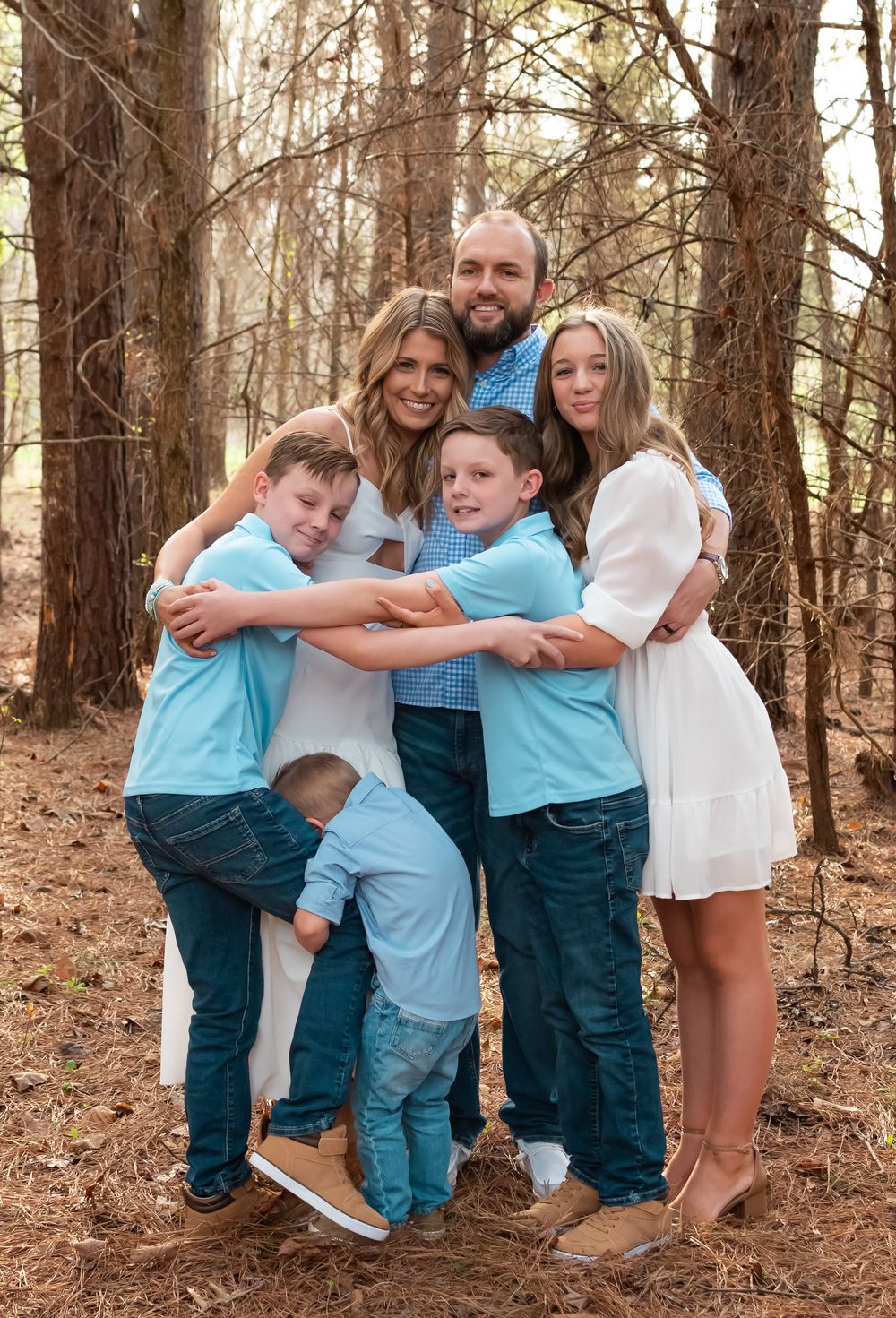 family hugging each out in the woods for a family photo session