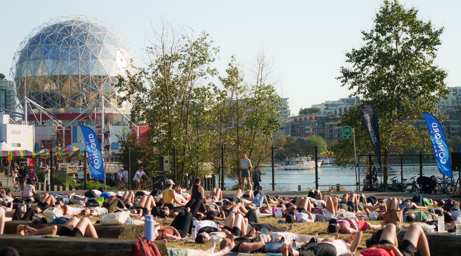 Large outdoor fitness class gathered near Science World dome in Vancouver.