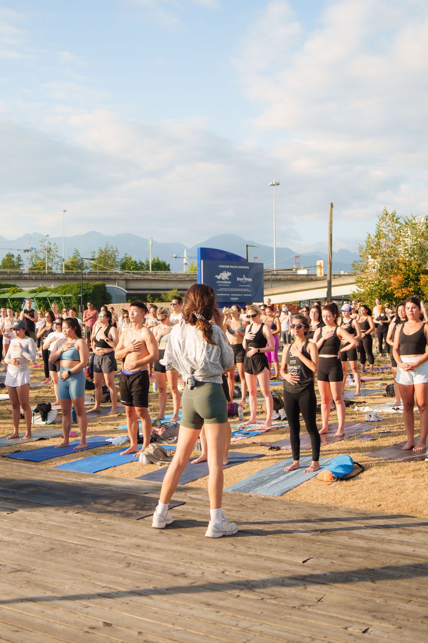 Large group workout class on yoga mats at outdoor waterfront location.