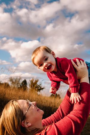 Upward angle portrait with baby against blue cloudy sky background.