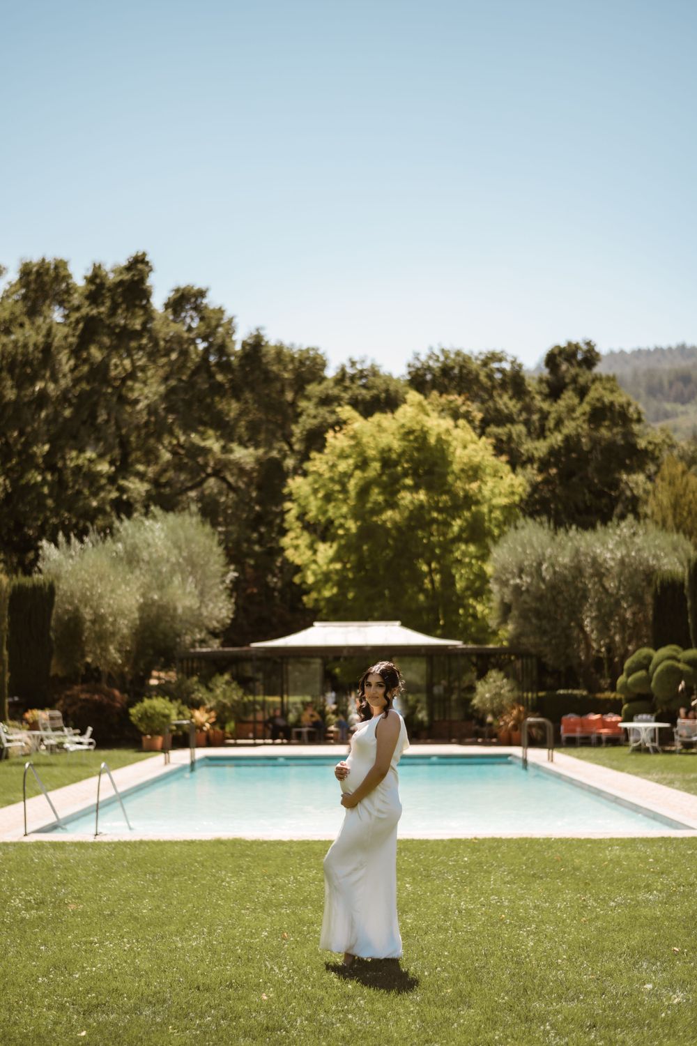 Outdoor wedding venue featuring pristine swimming pool and manicured lawn under blue sky.