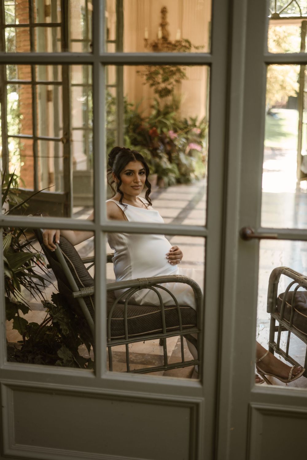 A tranquil scene on a sunlit porch with wicker furniture and potted plants.