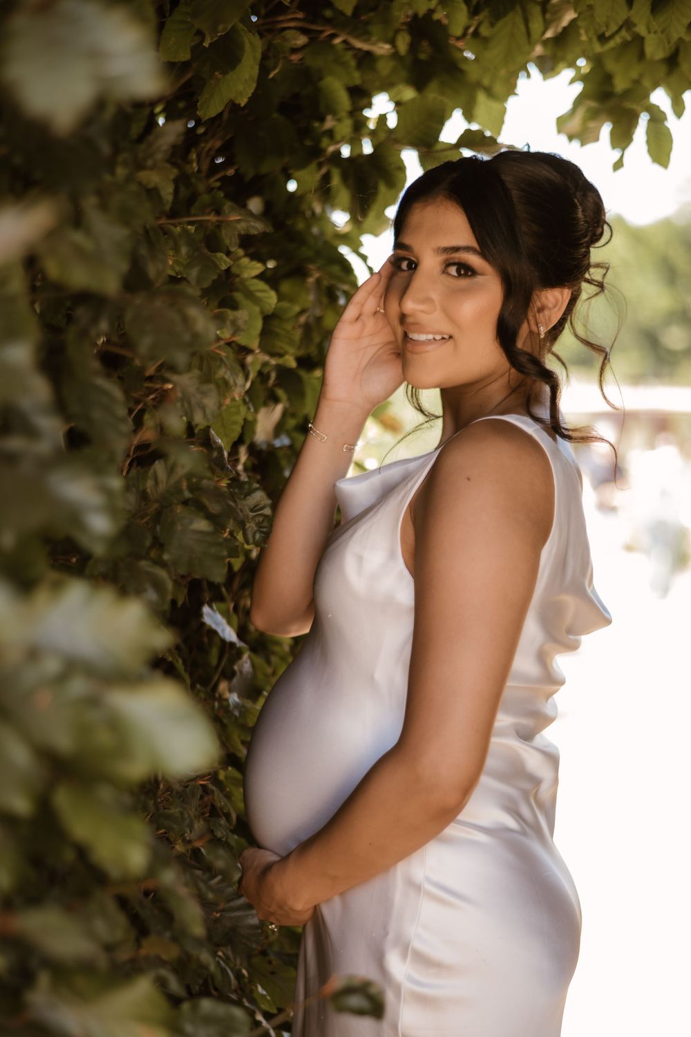 Soft natural lighting filters through leaves in an outdoor portrait setting.