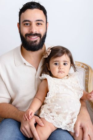 A parent and child in matching white outfits pose together for a series of sweet family portraits.