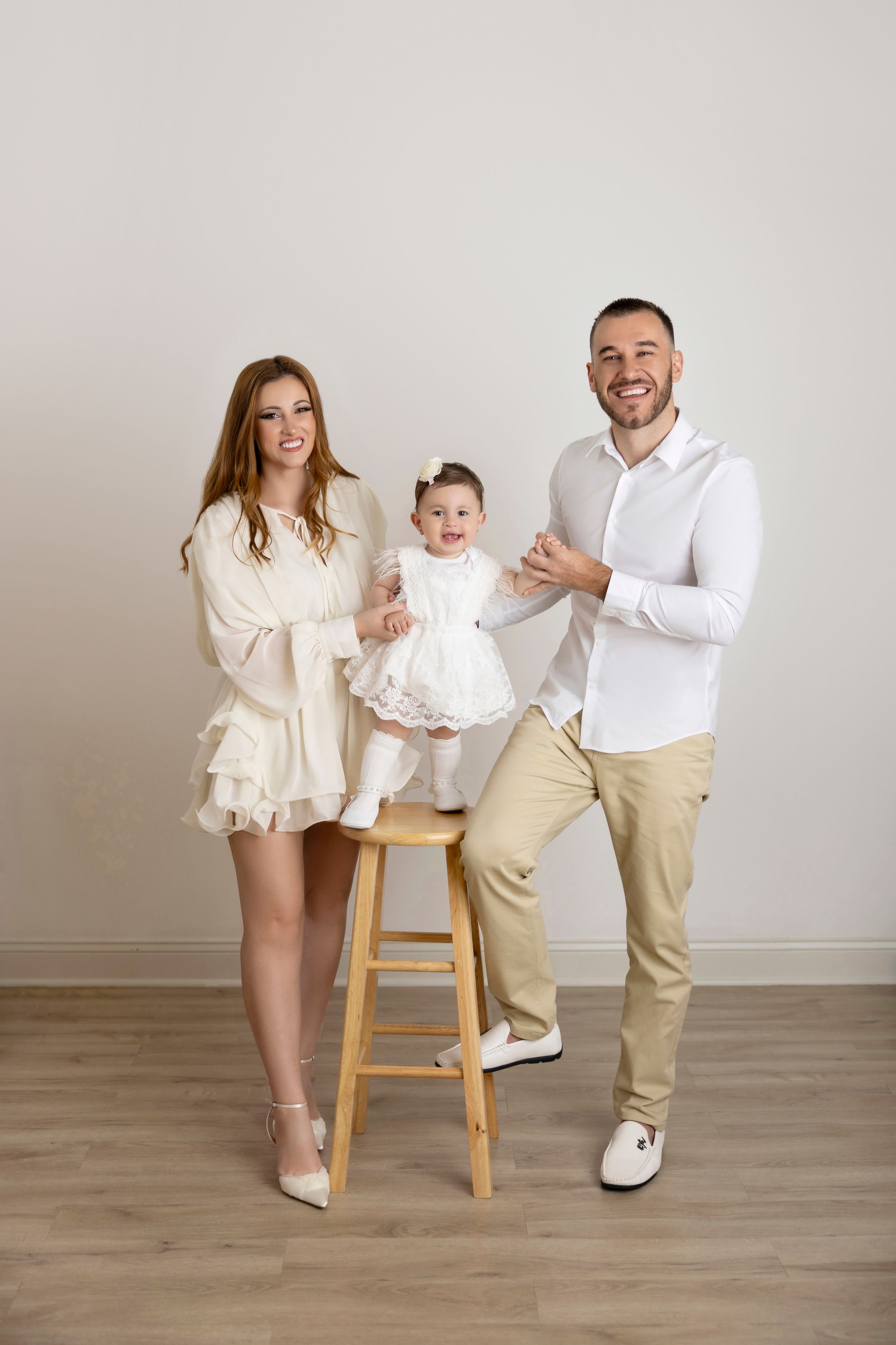 A series of five progressive family photos showing playful interactions around a wooden stool against a neutral background.
